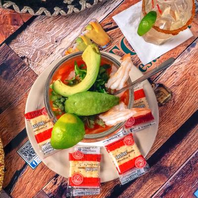 Mexican Shrimp Cocktail topped with avocado and a lime wedge, served with crackers.