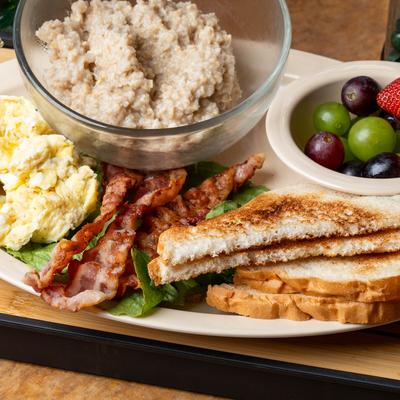 Scrambled eggs, bacon, toast, fresh fruit, and oat meal.
