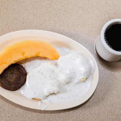 Biscuits with gravy, sausage patty, and melon.