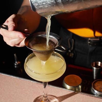 Bartender pouring a cocktail through a strainer.