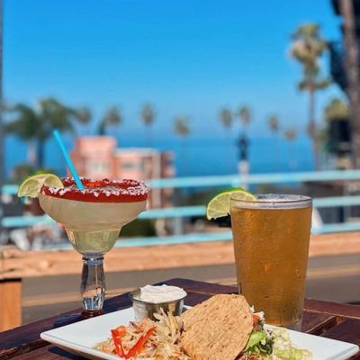 Chicken taco, served with salad, with a cocktail and beer on the side.