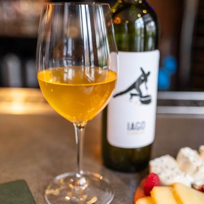 Georgian amber wine in glass in front of a bottle of Iago's Chinuri wine