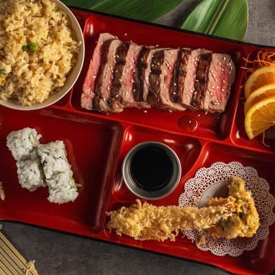 Beef teriyaki bento box,w ith shrimp tempura, sushi rolls, and rice.