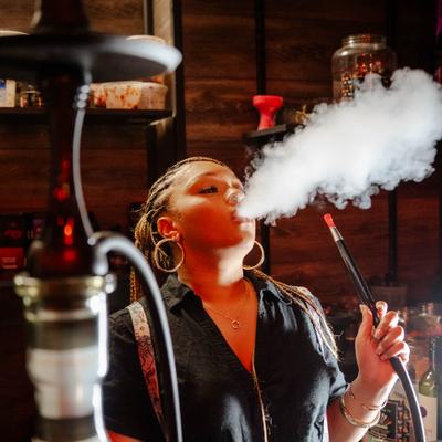 Person smoking a hookah in a lounge setting.