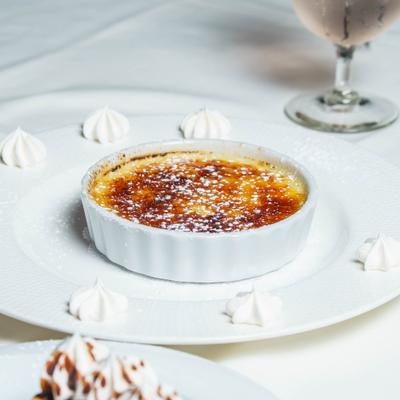 Creme brulee dessert served in a ramekin on a white plate.