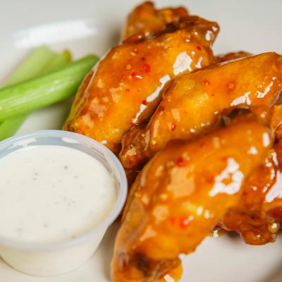 Wings coated in sauce and served with celery sticks and a dip, close-up.