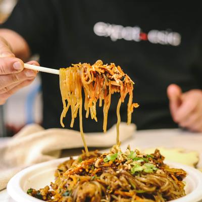 A person eating a noodle dish, hand close up.