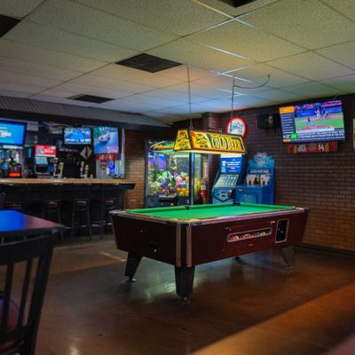 Game room with pool tables, arcades, and TVs.