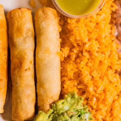 Taquitos, served with rice, beans, and guacamole.