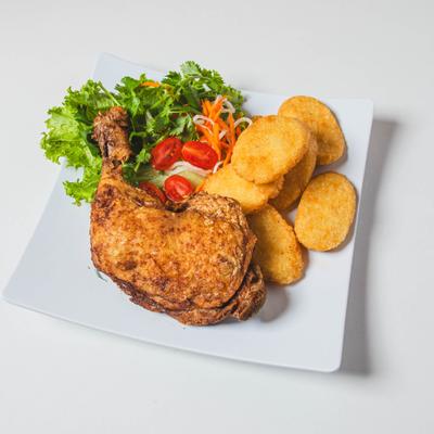 Fried chicken leg, nuggets, and side salad served on a white plate.