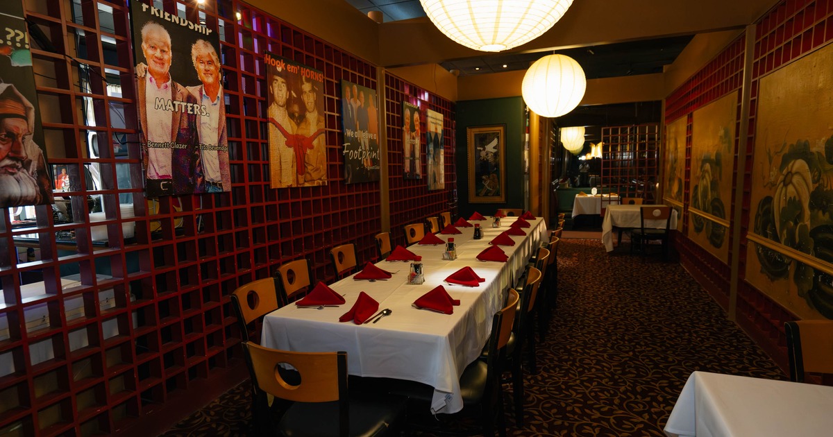 Restaurant interior with a long table, red napkins, lattice walls, and large ceiling lights