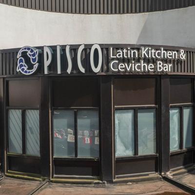 The storefront of Pisco Latin Kitchen displays windows under the restaurant sign.