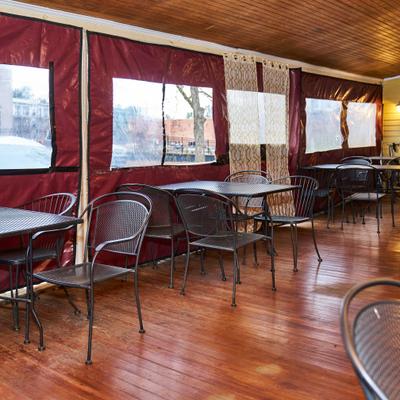 Enclosed patio with black metal furniture and wooden floors.