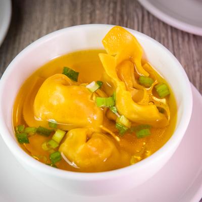 Wonton soup garnished with chopped green onions.