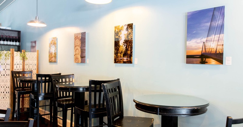 Interior, tall round tables and chairs by a wall decorated with pictures