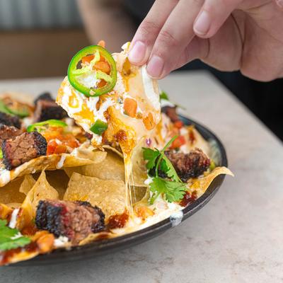 Burnt End Nachos, with cheese, salsa, lime cream, jalapenos, and cilantro.