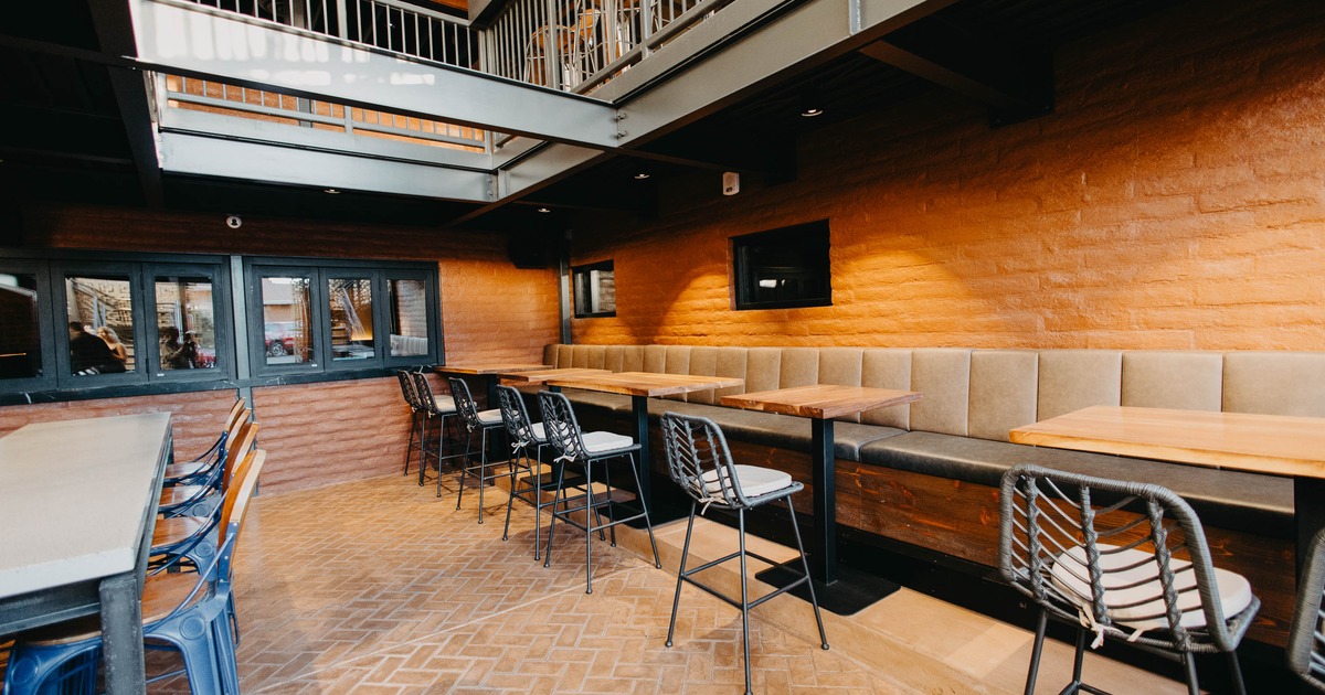 Indoor dining area with brick walls, cushioned bench, wooden tables