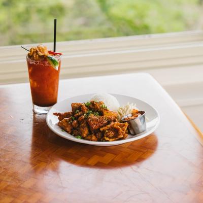 Bloody Mary and crispy chicken with rice served on a wooden table.