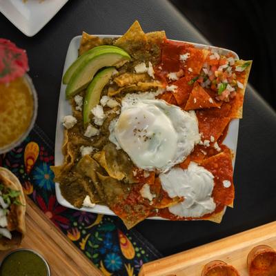 Corn tortillas with red and green sauces, eggs, sour cream, salsa, and cheese.