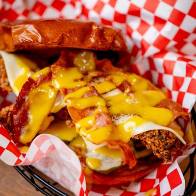 Chicken sandwich topped with bacon and melted cheese.