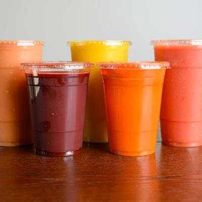 Assortment of smoothies served in clear plastic cups with lids.
