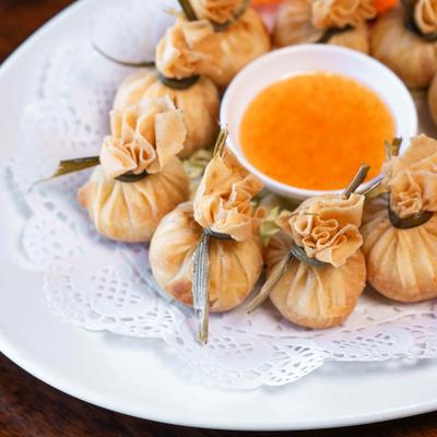 Thai money bag pastries with a side of sweet chili sauce.