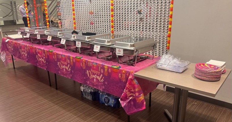 A well-arranged buffet table with multiple chafing dishes and plates for a celebration