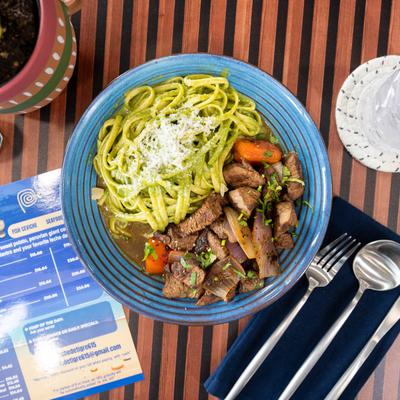 Peruvian Stir-Fried Beef with tomato and onion, served with linguine.