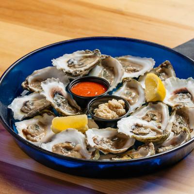 Raw Oysters on the Half Shell plate with lemon, horseradish, and red sauce.