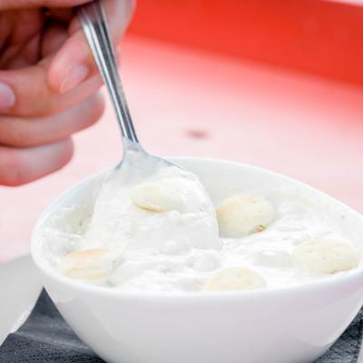 Closeup of a hand stirring the clam chowder with a spoon