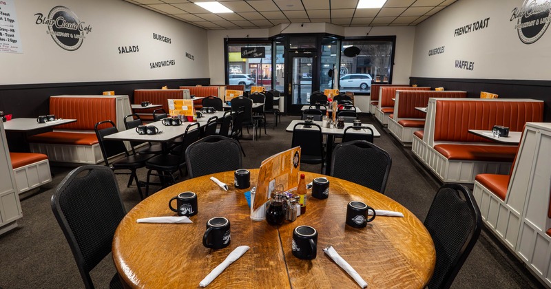 Interior - orange booths, a round wooden table in the foreground and black chairs