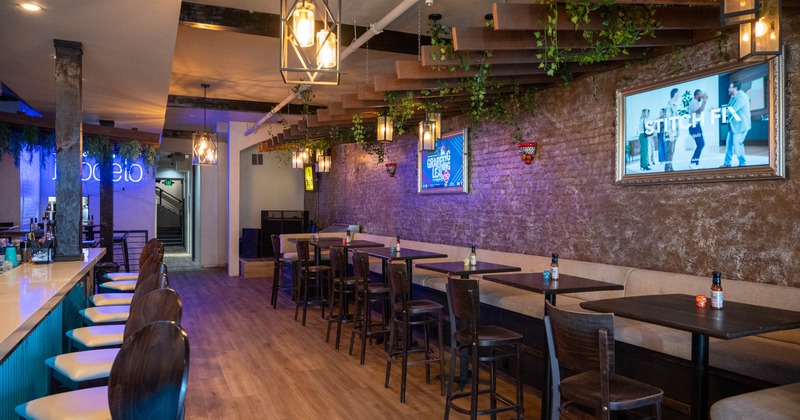 Interior, bar with stools on the left, banquette bench with tables and chairs on the right