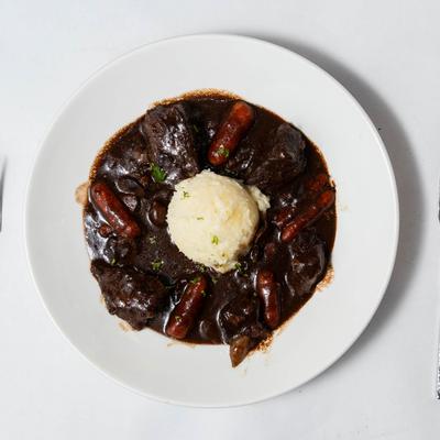 Beef Bourguignon presented with a central scoop of mashed potatoes.