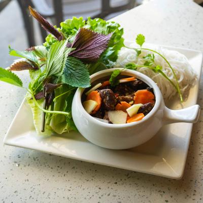 Grilled pork patties and pork belly served with rice vermicelli noodles and various green herbs.