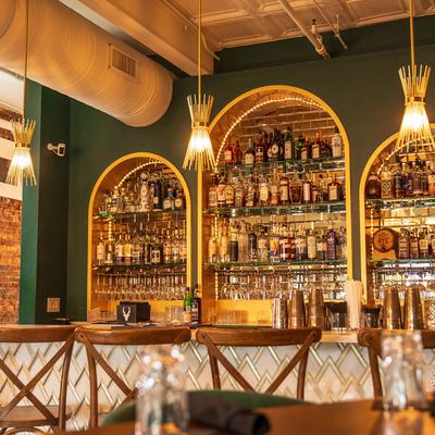 The bar area with stools, liquor bottles, and pendant lights.