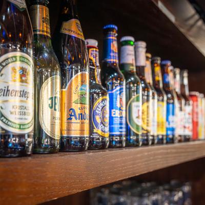 Lined up beer bottles on a bar shelf.