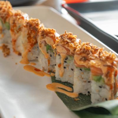 Hot Girl Roll topped with salmon, avocado, spicy mayo, sriracha, and fried onion.