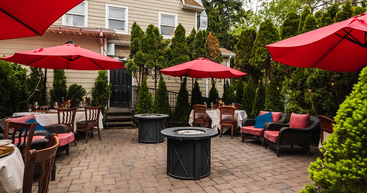 Outdoor patio with tables, red parasols, and fire pits