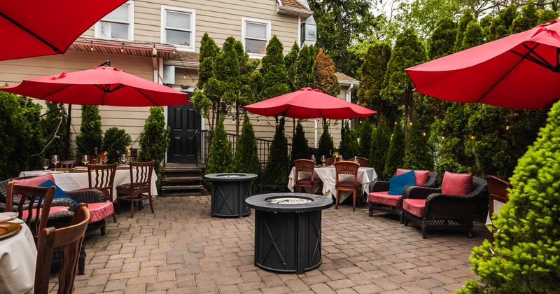 Outdoor patio with tables, red parasols, and fire pits
