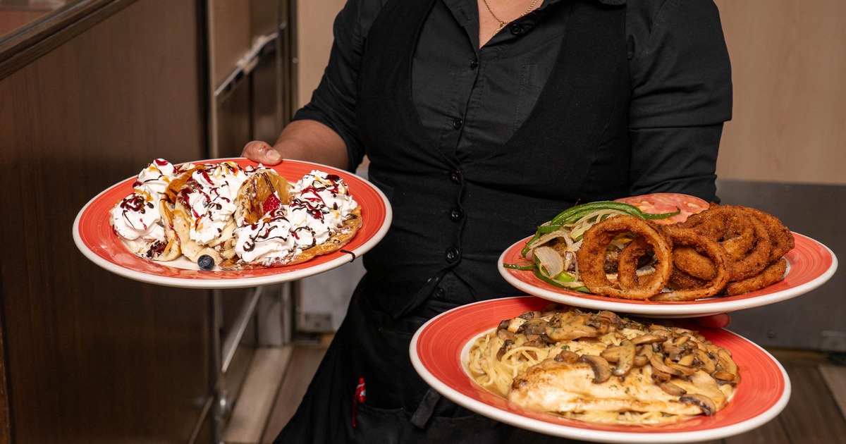A server holds plates filled with a variety of restaurant dishes