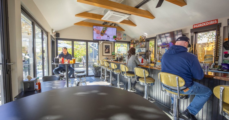 Interior, bar, bar stools lined up, a high table and chairs in the middle