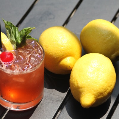 Deep orange cocktail with decorations and three lemons