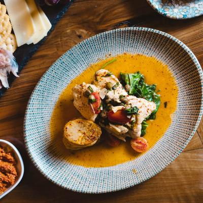 Lemon chicken plate surrounded by assorted food dishes, top view.