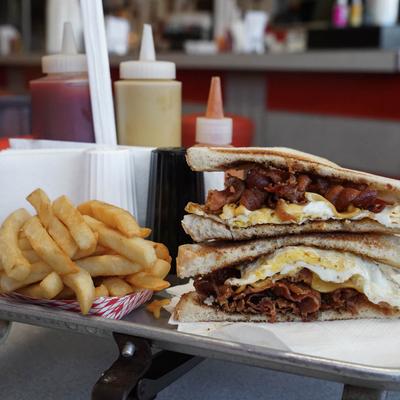 bacon egg and cheese sandwich on toast with fries.