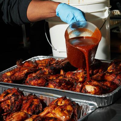 Pouring BBQ sauce on the meat.