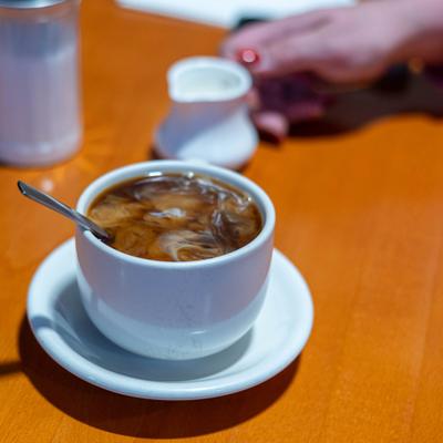 Cup of coffee  with cream being poured.