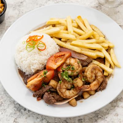 Stir fried beef and shrimp, with tomatoes, rice, and fries.