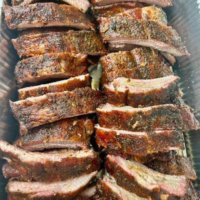 Smoked pork ribs arranged in a catering tray.