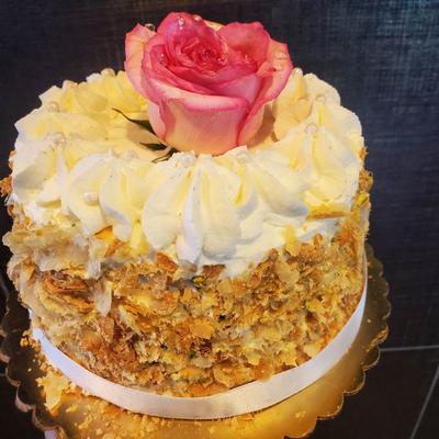 A beautifully decorated cake topped with a rose, elegantly presented on a gold plate.
