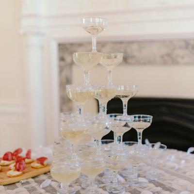 Champagne tower and appetizer boards placed on a table in a white room setting.